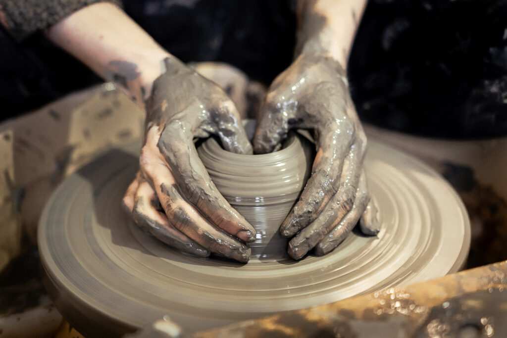 une ceramiste dans son atelier de grenoble realise un vase sur un tour a main. ceramique faite a la main par artisane